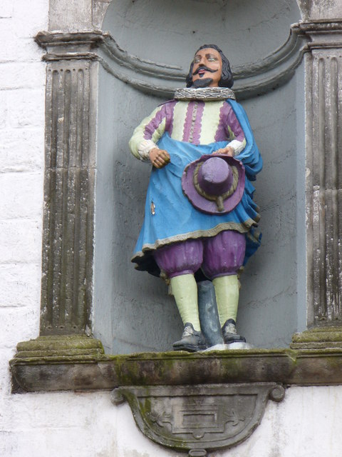 Statue of a man with a moustache and pointy beard, with clothing painted blue and purple.