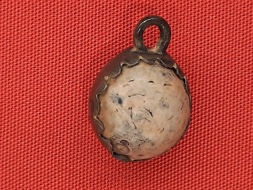 Photo of a round stone secured in a silver pendant setting.